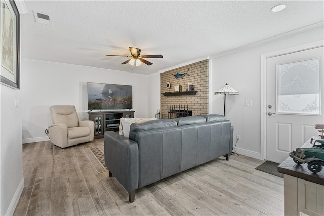 living room with ceiling fan, light hardwood / wood-style flooring, ornamental molding, and a textured ceiling