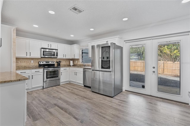 kitchen featuring stainless steel appliances, white cabinetry, light stone counters, french doors, and light wood-type flooring