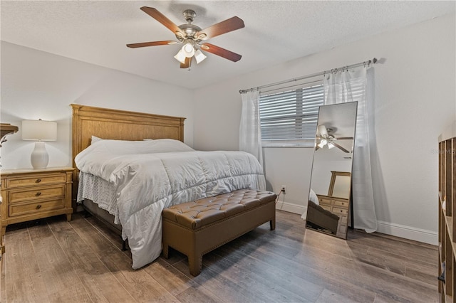 bedroom featuring dark hardwood / wood-style flooring, a textured ceiling, and ceiling fan