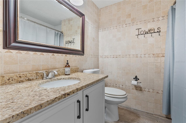 bathroom with tile walls, vanity, and toilet