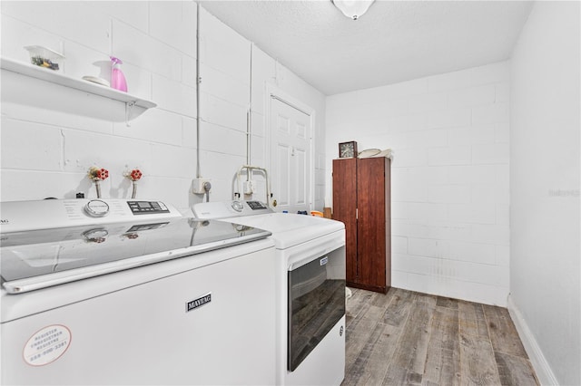 laundry room with separate washer and dryer, light wood-type flooring, and a textured ceiling