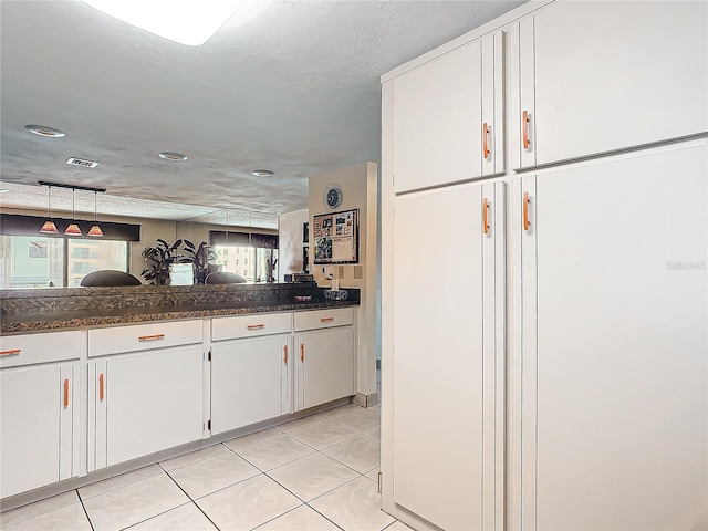 kitchen featuring white cabinets, light tile patterned flooring, and decorative light fixtures