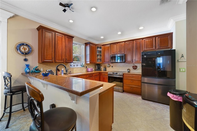 kitchen with tasteful backsplash, a breakfast bar, ornamental molding, and appliances with stainless steel finishes