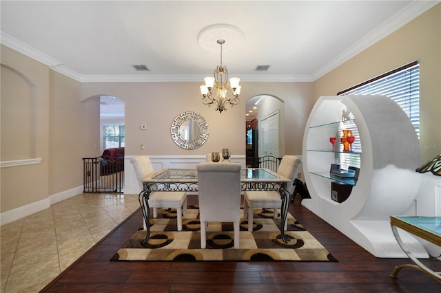 dining area with tile patterned flooring, ornamental molding, and an inviting chandelier