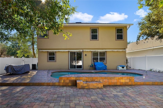 rear view of property featuring a patio and a hot tub