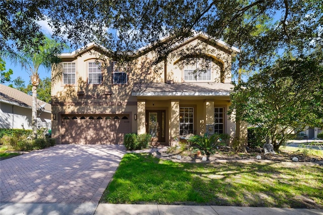 view of front of home with a garage, decorative driveway, a front yard, and stucco siding