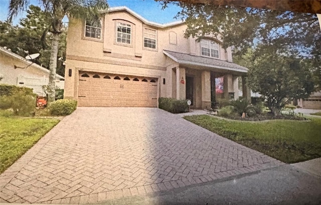 view of front of house with a garage, decorative driveway, and stucco siding