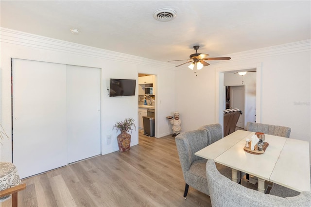 dining room featuring ceiling fan, crown molding, and light wood-type flooring