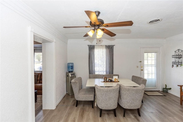 dining area featuring a healthy amount of sunlight, crown molding, and light hardwood / wood-style floors