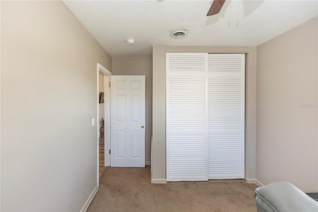 bedroom featuring ceiling fan, light colored carpet, and a closet