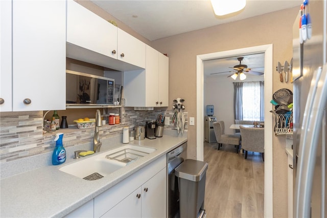 kitchen with stainless steel dishwasher, decorative backsplash, sink, and white cabinetry