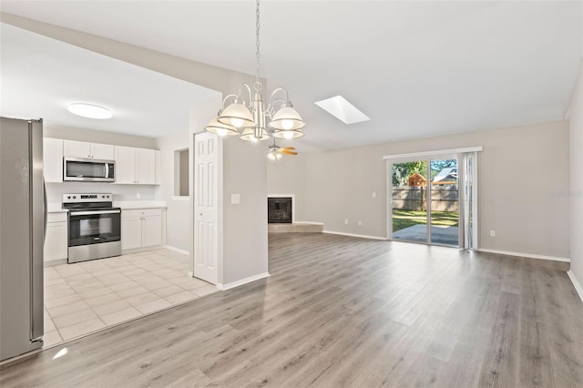 kitchen with stainless steel appliances, pendant lighting, light hardwood / wood-style flooring, a chandelier, and white cabinetry