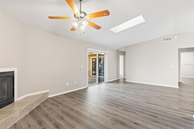 unfurnished living room with ceiling fan, dark hardwood / wood-style flooring, and vaulted ceiling with skylight