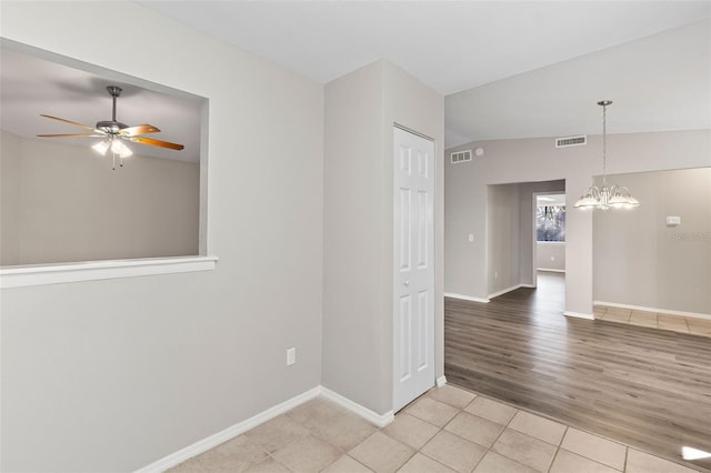 unfurnished room with ceiling fan with notable chandelier and light tile patterned flooring