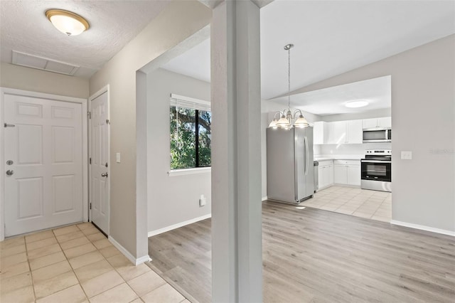 tiled foyer with a chandelier and vaulted ceiling