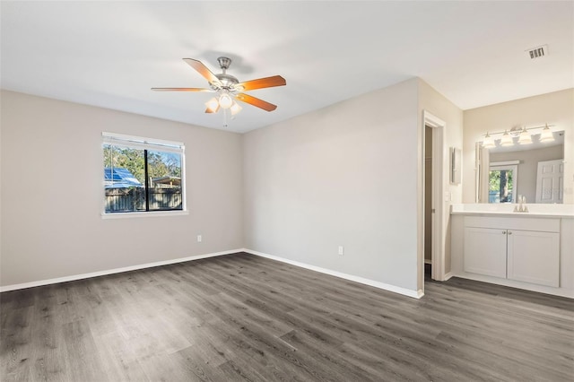 unfurnished bedroom with sink, ceiling fan, ensuite bathroom, and multiple windows