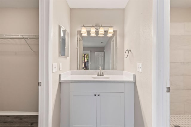 bathroom with hardwood / wood-style flooring, vanity, and a tile shower