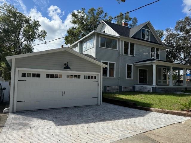 view of front of house featuring covered porch, a garage, and a front lawn