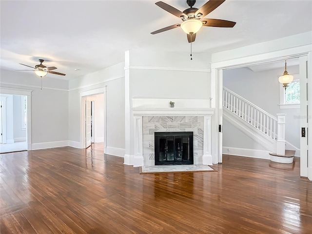 unfurnished living room featuring dark hardwood / wood-style flooring, ceiling fan, and a premium fireplace