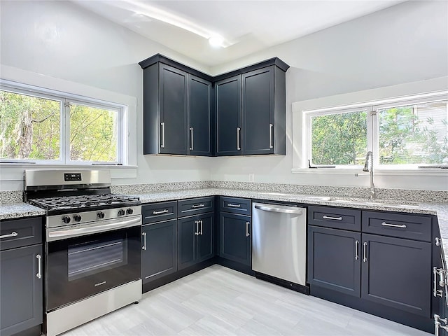 kitchen with light stone countertops, stainless steel appliances, and sink