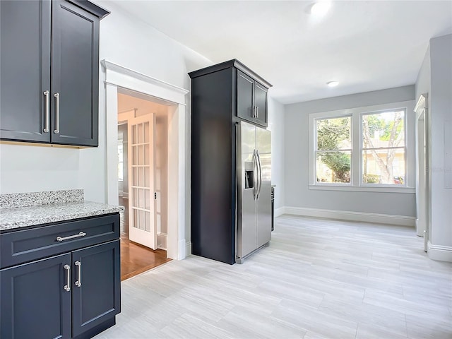 kitchen with light stone countertops and stainless steel fridge with ice dispenser