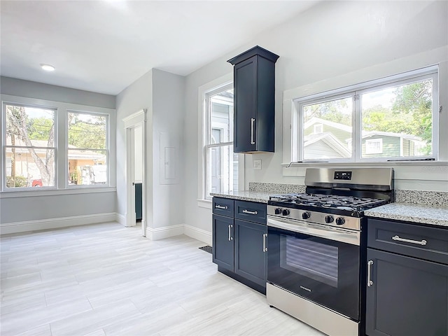 kitchen featuring light stone countertops, gas range, a wealth of natural light, and blue cabinetry