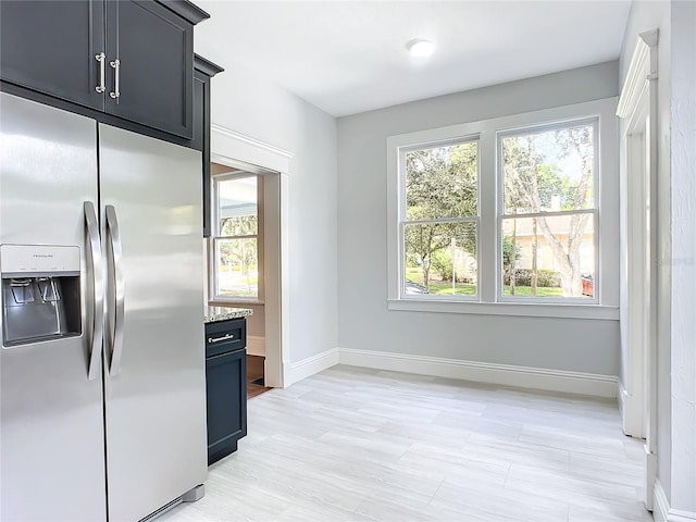 kitchen featuring stainless steel refrigerator with ice dispenser and light stone counters