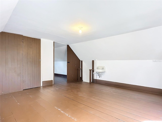 bonus room with wood walls, hardwood / wood-style floors, and vaulted ceiling