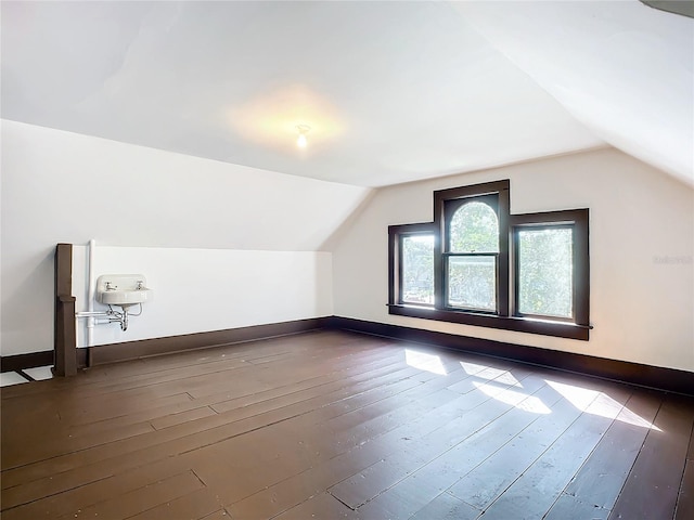 additional living space featuring dark wood-type flooring and lofted ceiling