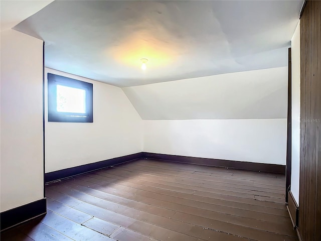 additional living space featuring vaulted ceiling and dark wood-type flooring