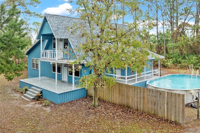 rear view of house featuring a swimming pool side deck and a balcony