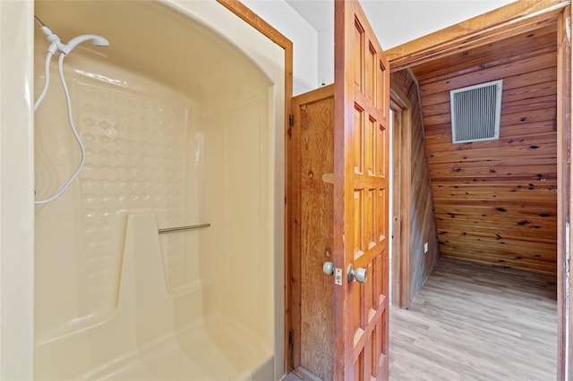 bathroom featuring a shower, wood-type flooring, and wood walls