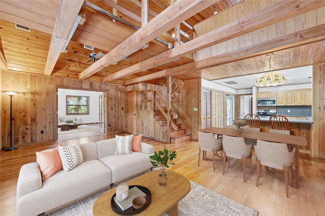 living room with beamed ceiling, light wood-type flooring, wooden walls, and wood ceiling