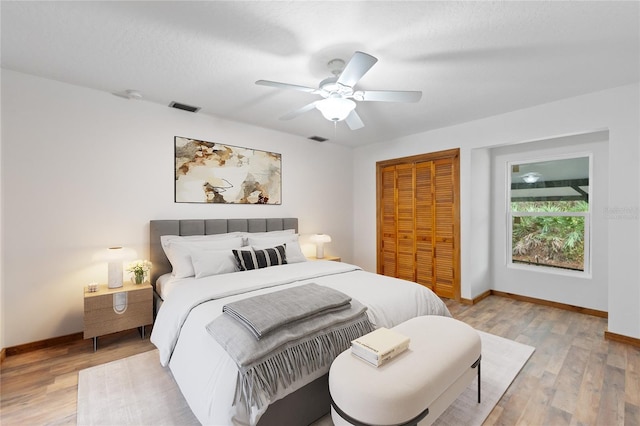 bedroom featuring ceiling fan, light hardwood / wood-style floors, a textured ceiling, and a closet