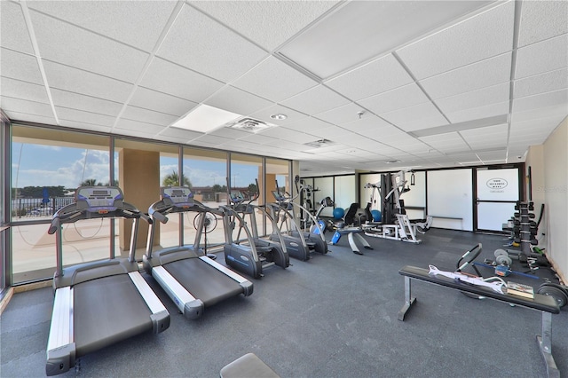 gym featuring a drop ceiling and a wall of windows