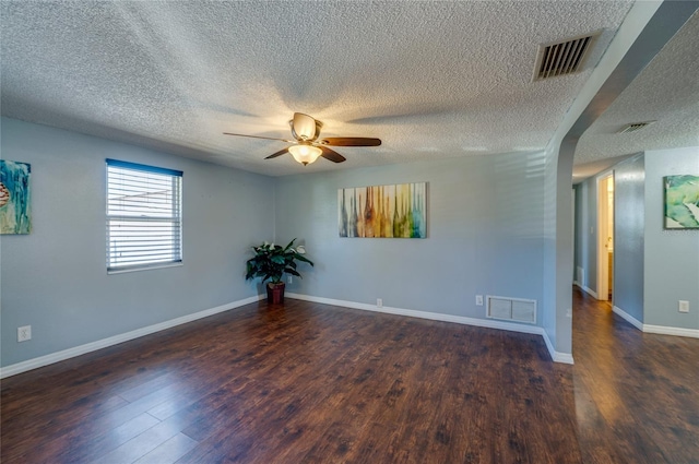 empty room with a textured ceiling, dark hardwood / wood-style flooring, and ceiling fan