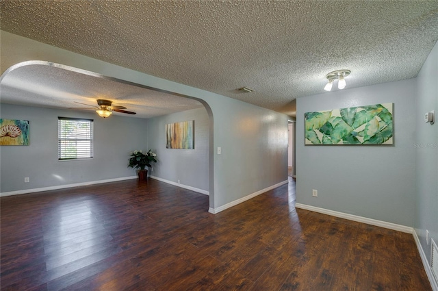 empty room with a textured ceiling, ceiling fan, and dark hardwood / wood-style floors