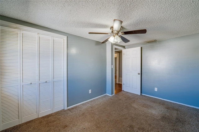 unfurnished bedroom with carpet flooring, ceiling fan, a textured ceiling, and a closet