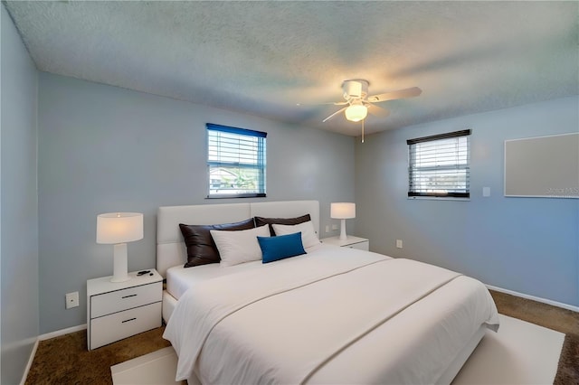 bedroom with dark colored carpet, ceiling fan, and a textured ceiling