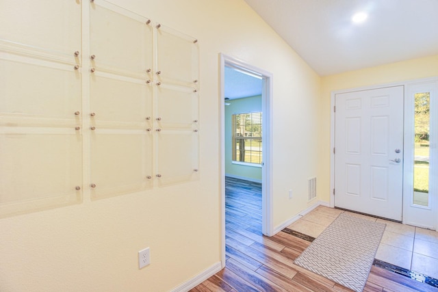 foyer entrance with light hardwood / wood-style floors and vaulted ceiling