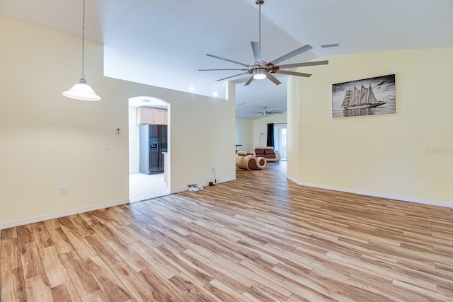 unfurnished living room featuring light hardwood / wood-style floors, vaulted ceiling, and ceiling fan