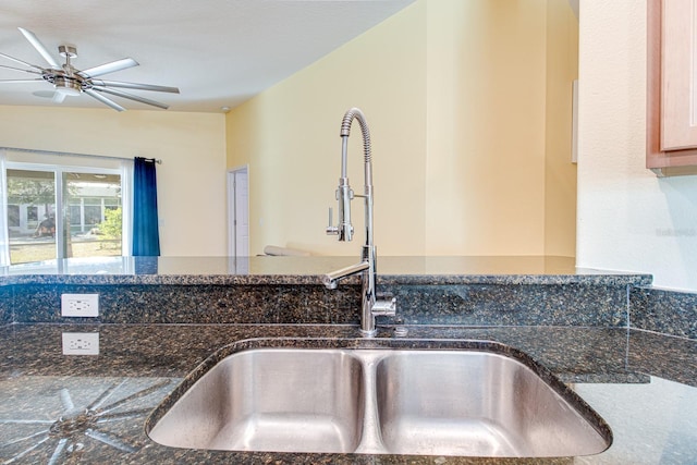 interior details featuring ceiling fan, sink, and dark stone counters