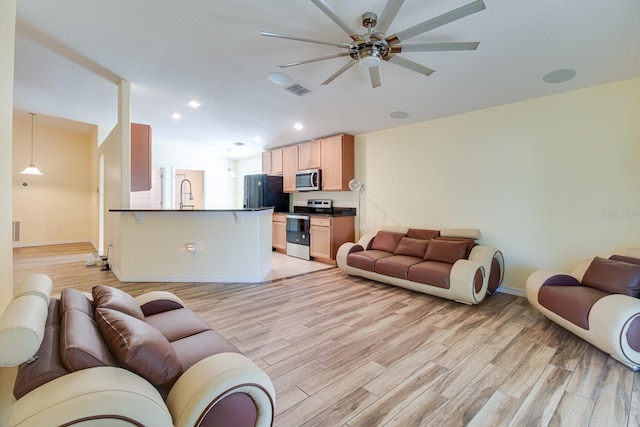 living room featuring light hardwood / wood-style flooring, ceiling fan, and sink