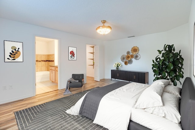 bedroom with ensuite bathroom and hardwood / wood-style floors