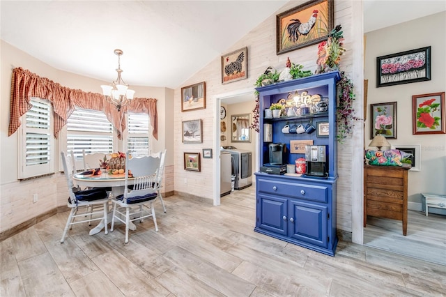 dining room featuring separate washer and dryer, a chandelier, and vaulted ceiling