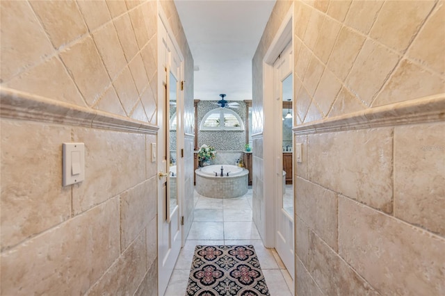 bathroom with tiled bath, tile patterned floors, and tile walls