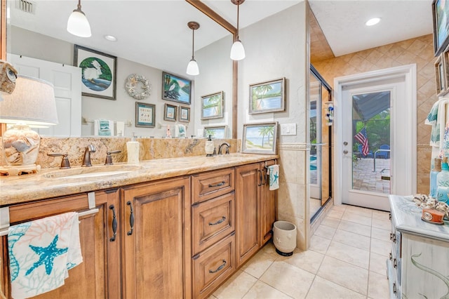 bathroom with tile patterned floors, vanity, a shower with shower door, and tile walls