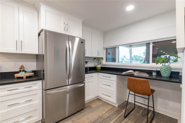 kitchen with stainless steel fridge, light hardwood / wood-style flooring, and white cabinets