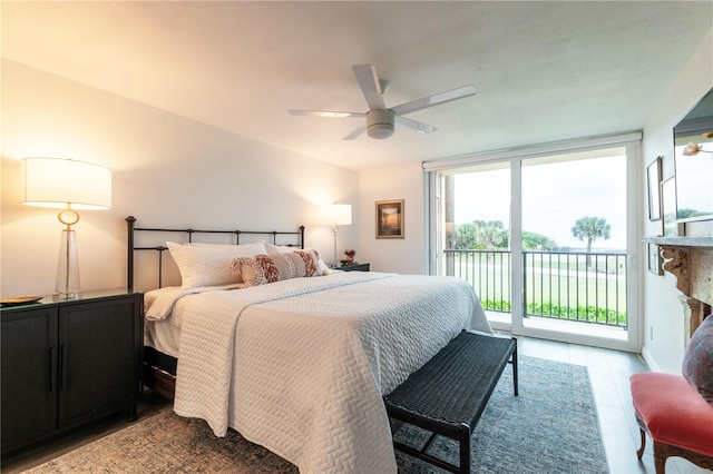 bedroom with access to outside, ceiling fan, light wood-type flooring, and a wall of windows