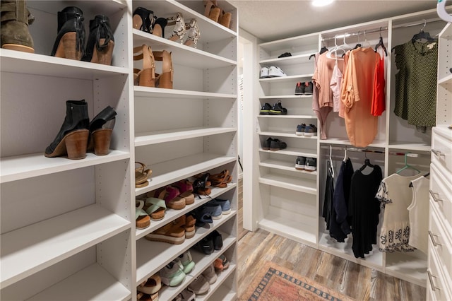 walk in closet with light hardwood / wood-style floors